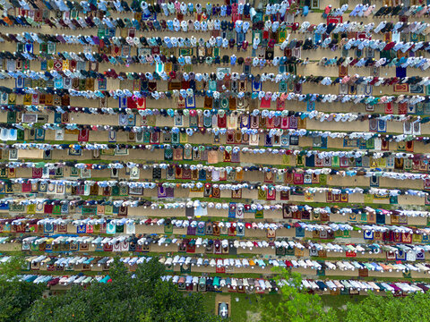 Joypurhat, Bangladesh - 28 May 2026: Aerial view of a large crowd of Muslim worshippers performing Eid al-Adha prayers on colorful mats in an open field.