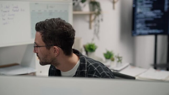 Concentrated man with eyeglass working on personal computer server security and cyber data privacy system at desk in the office workspace.