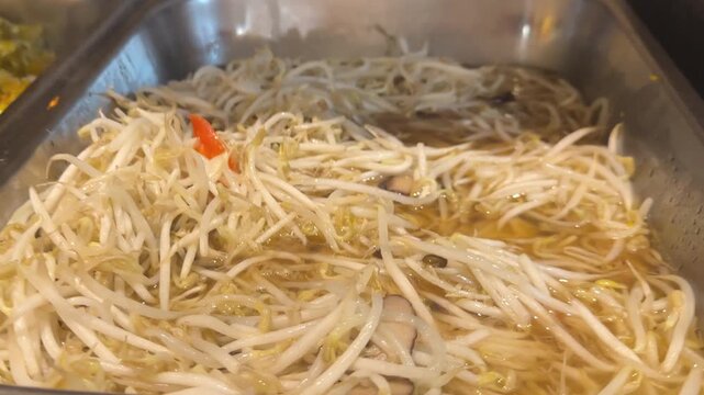 Close up video of spicy stir fried bean sprouts with mushrooms and red chilies in hot pan