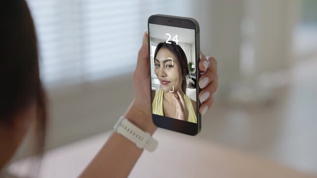 Asia people young adult woman using digital device screen phone scan age app look at camera smart bioage face online test agentic AI. Asian female Health care facial skin anti aging beauty tracker.