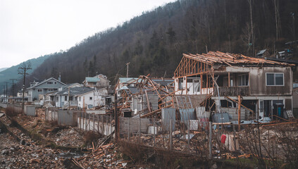 Fototapeta premium 山裾の住宅地で津波後の壊れた家屋と瓦礫が広がる風景
