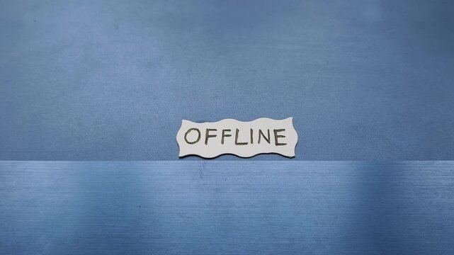 Offline word written on white paper placed on top of personal laptop computer keyboard. Digital detox, work life balance, disconnected from work, support unavailable and communication issues concept.