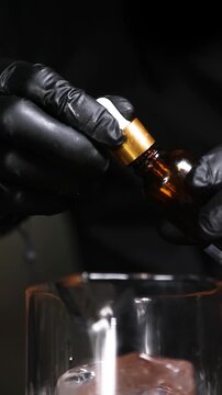 Barman a&ntilde;adiendo gotas arom&aacute;ticas a una copa de c&oacute;ctel artesanal. Barman profesional a&ntilde;adiendo amargos arom&aacute;ticos a un c&oacute;ctel. T&eacute;cnica de bar precisa, servicio artesanal de primera calidad.