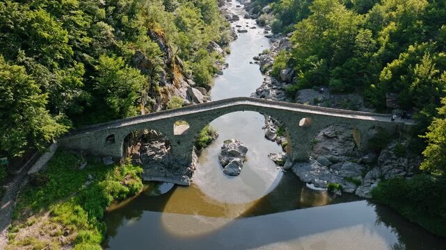 Devils bridge dyavolski most stone arch river canyon canyon green forest trees drone aerial view bulgaria rhodope mountains medieval historical landmark water reflection travel destination
