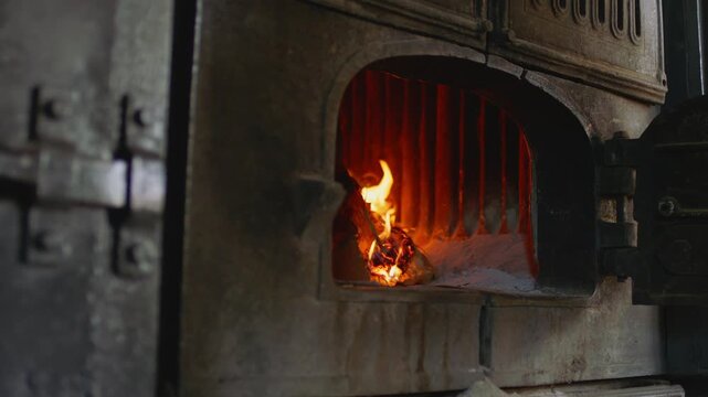 Burning firewood inside metal stove furnace, warm rustic interior