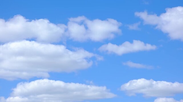 Bright blue sky with fluffy white clouds. The scene conveys a serene, sunny atmosphere with varying cloud shapes and sizes. Natural tranquil background.