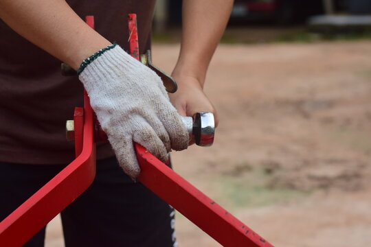 Agricultural machinery assembler using socket wrenches and hydraulic components. High-resolution photograph.