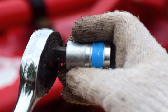 Agricultural machinery assembler using socket wrenches and hydraulic components. High-resolution photograph.