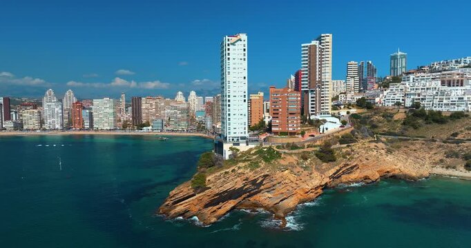 Benidorm city resort skyscraper building rocky cliff coast line beach turquoise sea water drone aerial view spain mediterranean coastal landscape summer travel destination tourism hotels