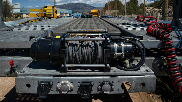 Close up view of electric winch on car hauler truck trailer with steel cable ready for use in vehicle transport operation