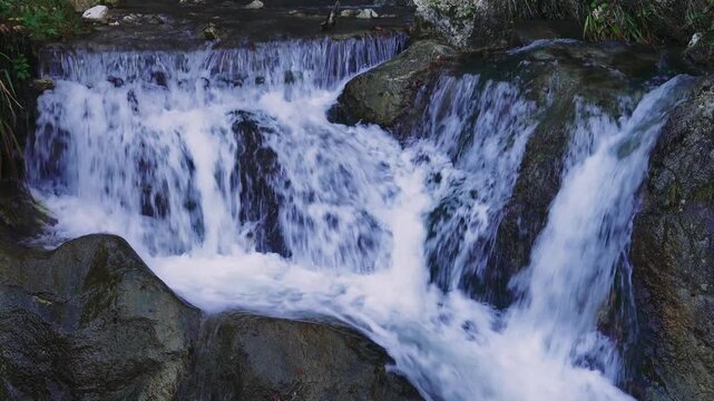 Small Waterfall Flowing Over Rocks in Static Close-Up Shot