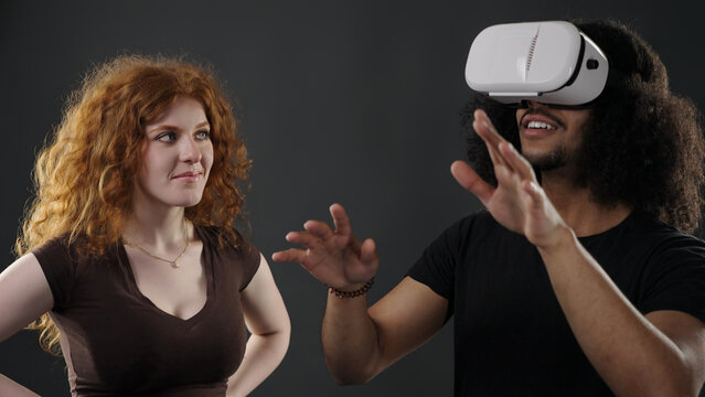 Couple engaging with VR technology, one experiencing a virtual world while other observing