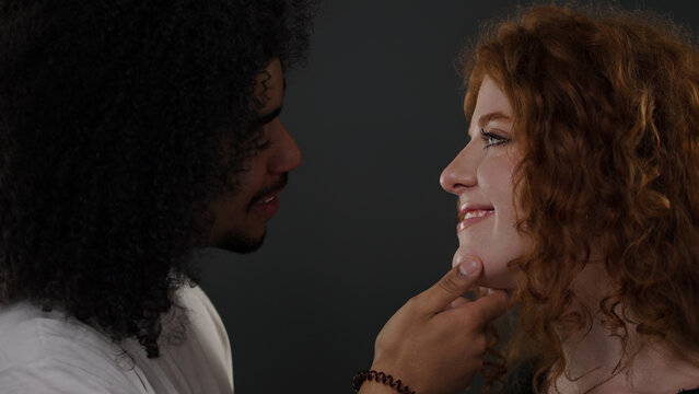 Couple sharing a tender moment, man touching woman's chin while smiling