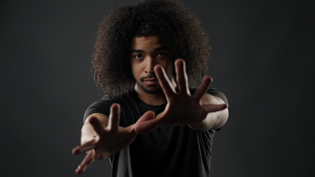 Young man with afro hair extending hands, signaling to stop or creating a barrier