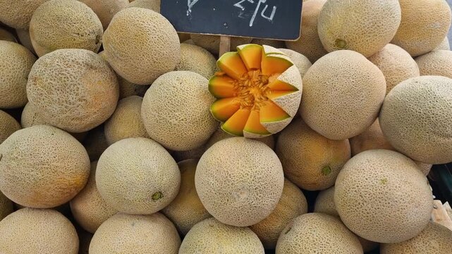Close-up of neatly presented honey melons for sale at a local street market in Santiago de Chile, showcasing fresh produce and vibrant colors in an urban food market