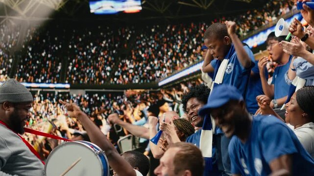 Blue soccer supporters cheering together in crowded stadium during live football match in the supporter section with supporter chants.