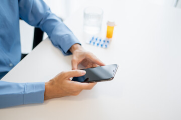 Fototapeta premium Man using mobile health app and AI technology for medication health tracking with pills and vitamins.