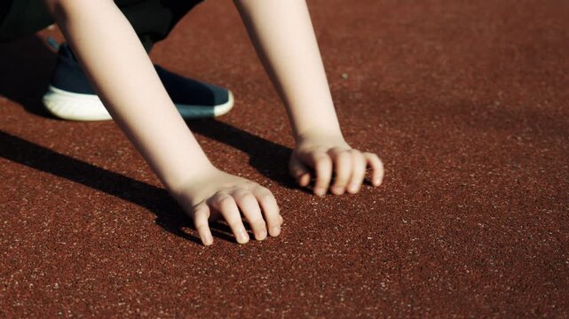 Children's pens touch the safe rubber crumb coating on the playground, in kindergarten, at school or at the stadium and show the class. Close-up.