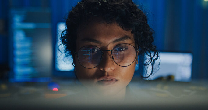 Close-up Black female programmer with code reflection in glasses working late in home office at night. Cybersecurity, AI algorithm, Network security, software developer, serious face, burnout concept.