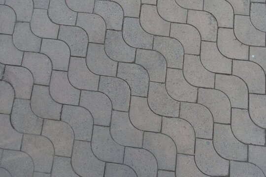 Texture of rounded gray concrete paver blocks with waves like pattern