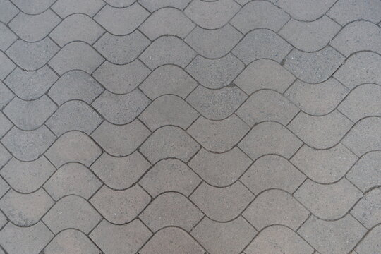 Texture of rounded gray concrete paver blocks with waves like pattern