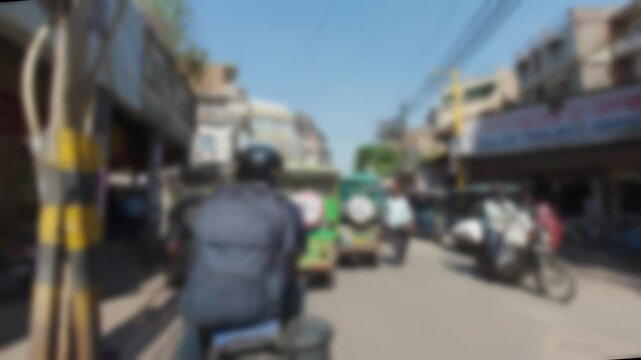 Blurred pedestrian view of busy shopping street in Old Delhi with local traffic, market activity and urban life in historic district during daytime timelapse.