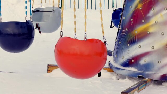 Bright plastic swing seats hang motionless in a snow-covered playground. The vivid colors contrast with the white snow, evoking a sense of anticipation and quiet before play