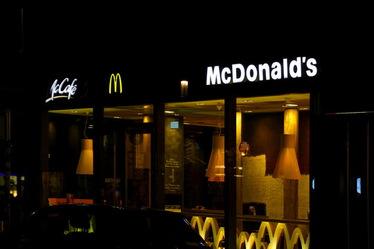 Leipzig, Germany, May 3, 2026: Nighttime View of McDonald's and McCafe Storefront with Illuminated Signs