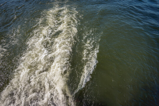 Ship's wake in the water of a Dutch river on a sunny day in springtime.