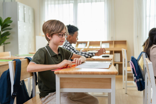 Young elementary boy focusing on school work at desk, Dedicated student using a ruler in the classroom, Focused primary school student studying in modern classroom