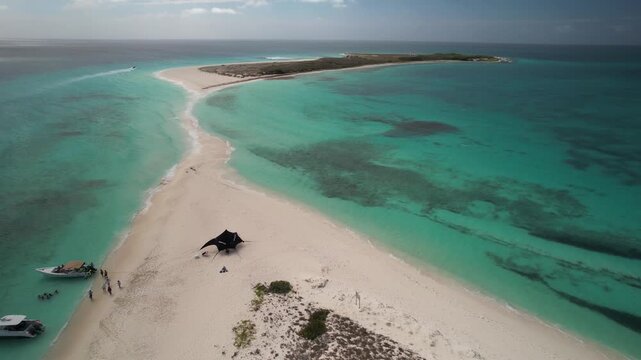 Aerial flyover Caribbean island, boats and visitors on pristine beach, Cayo de Agua, Los Roques Archipelago.