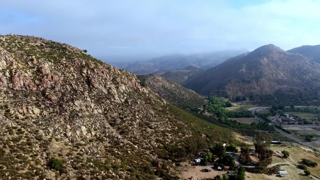 Rocky hills and sparse vegetation under a cloudy sky in Temescal Valley. Ideal for nature documentaries or geographic studies.