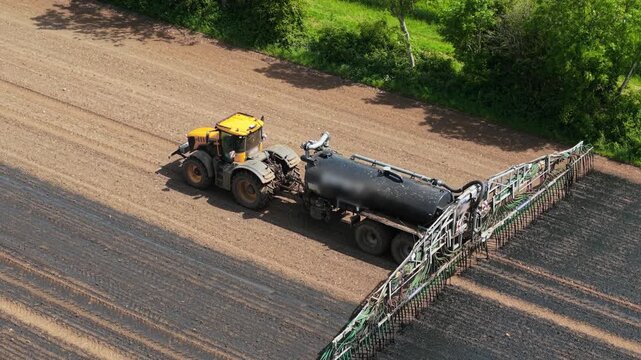 Tractor applying liquid organic manure for soil fertility improvement. Precision nutrient distribution supporting crop productivity and sustainable farming. Modern farm machinery operating