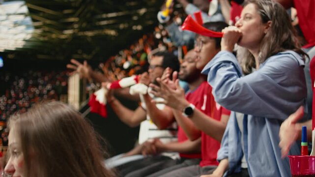 Passionate woman football supporter cheering with red team crowd in stadium stands during intense live soccer match, football equality.