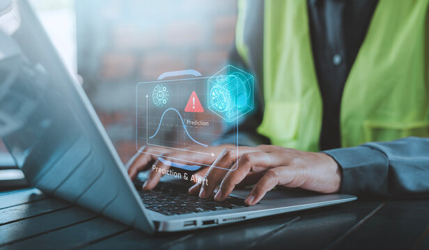 AI predictive maintenance and condition monitoring concept engineer typing on laptop with holographic electric motor machine failure curve graph and predictive alert dashboard