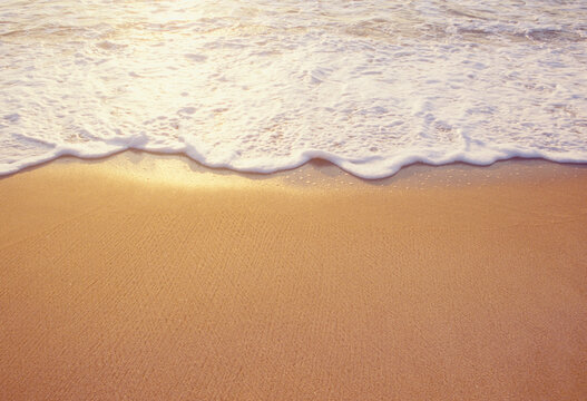 Close-up of sea wave washing sandy beach