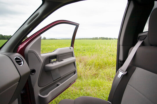 Grassy field seen out pickup truck open door