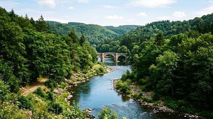 Fototapeta premium Ancient stone bridge over winding river in lush green valley