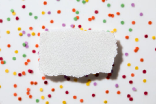 Torn white paper on confetti background