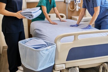 Obraz premium Hospital staff changing bed linens in modern patient room, professional healthcare team preparing clean clinical ward with efficient, hygienic, compassionate care
