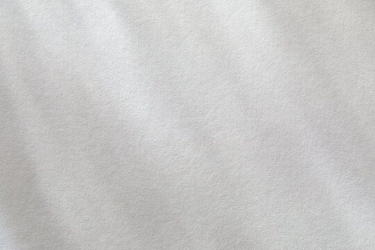 Dappled light on textured white paper