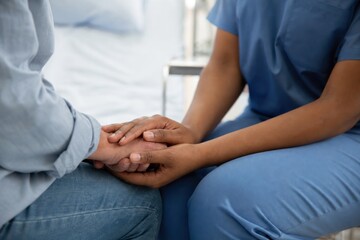Obraz premium Nurse holding patient hands during compassionate healthcare consultation in bright modern hospital room, reassuring, supportive, professional close-up care moment