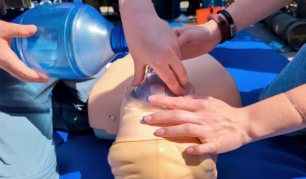 Children learning first aid during cpr training on a medical mannequin. Kids practicing artificial ventilation using an ambu bag resuscitator.