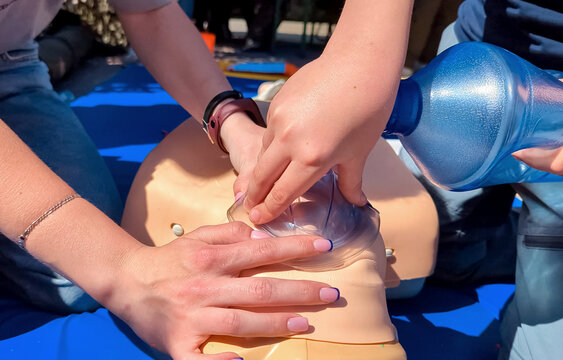 Children learning first aid during cpr training on a medical mannequin. Kids practicing artificial ventilation using an ambu bag resuscitator.