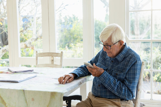 elderly man sitting at table using smart phone