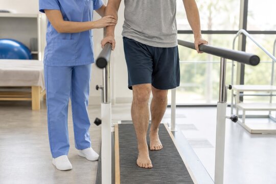 Physical therapist assisting adult male patient walking on parallel bars in modern rehabilitation clinic, professional supportive recovery care with calm hopeful atmosphere