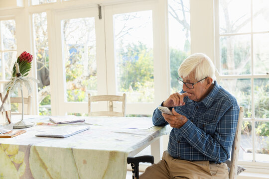 elderly man sitting at table using smart phone