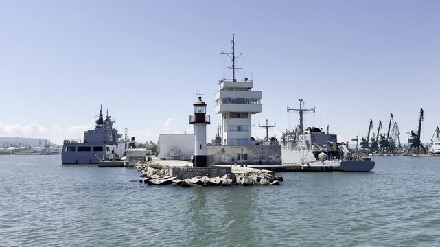 Warships in the port of Varna, Bulgaria. Lighthouse and naval vessels at harbor with clear blue sky