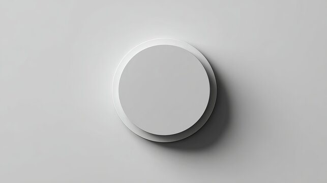 A minimalist white circular object with a subtle shadow on a plain gray background