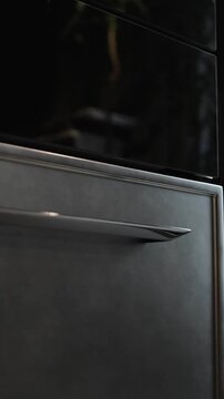 Vertical video. Close-up of modern kitchen cabinets with metal handles in contemporary interior design. Slow camera movement across stylish kitchen furniture. Slow motion 4K video.